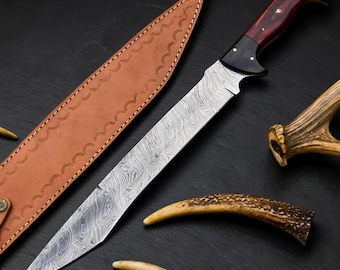 May include: A fixed-blade knife with a patterned Damascus steel blade and a dark red and black handle with silver pins. The knife is accompanied by a tan leather sheath featuring decorative stitching and two pieces of brown deer antler.