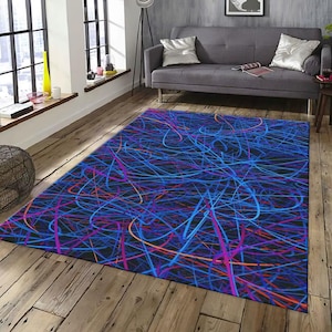 May include: A rectangular area rug with a dark background and a vibrant abstract design. The rug features a chaotic pattern of blue, purple, and orange lines, creating a dynamic and modern aesthetic. The rug is placed on a wooden floor.