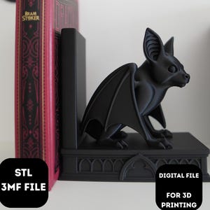 May include: A black bat-shaped bookend with detailed wings and ears, positioned on a decorative base. A red and gold book with the title "Dracula" stands next to the bookend. The image also includes the text "STL 3MF FILE" and "DIGITAL FILE FOR 3D PRINTING".