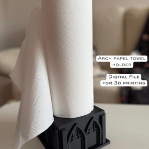 May include: Black paper towel holder with an arched design, holding a roll of white paper towels. The holder has a square base and a black top. Text on the image reads "ARCH PAPEL TOWEL HOLDER" and "DIGITAL FILE FOR 3D PRINTING."