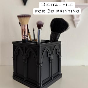 Puede incluir: Soporte negro para brochas de maquillaje de estilo gótico con múltiples compartimentos, que contiene varias brochas de maquillaje. El soporte tiene un diseño arqueado y el texto "DIGITAL FILE FOR 3D PRINTING".