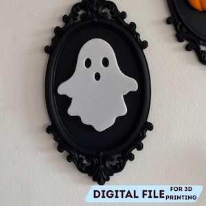 May include: A white ghost-shaped decoration inside a black ornate frame. The frame is oval and has a detailed, decorative border. The text "STL + 3MF FILE" and "DIGITAL FILE FOR 3D PRINTING" are visible.