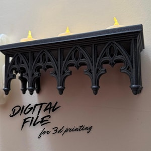 May include: Black, gothic-style shelf with three battery-operated candles. The shelf has an ornate, arched design and is mounted on a light-coloured wall. Text on the wall reads "DIGITAL FILE for 3d printing."