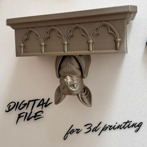 Może przedstawiać: Metaliczna półka z łukowatym wzorem, z nietoperzem wiszącym do góry nogami. Tekst "DIGITAL FILE" i "for 3d printing" jest wyświetlany czcionką odręczną. Półka jest zamontowana na białej ścianie.