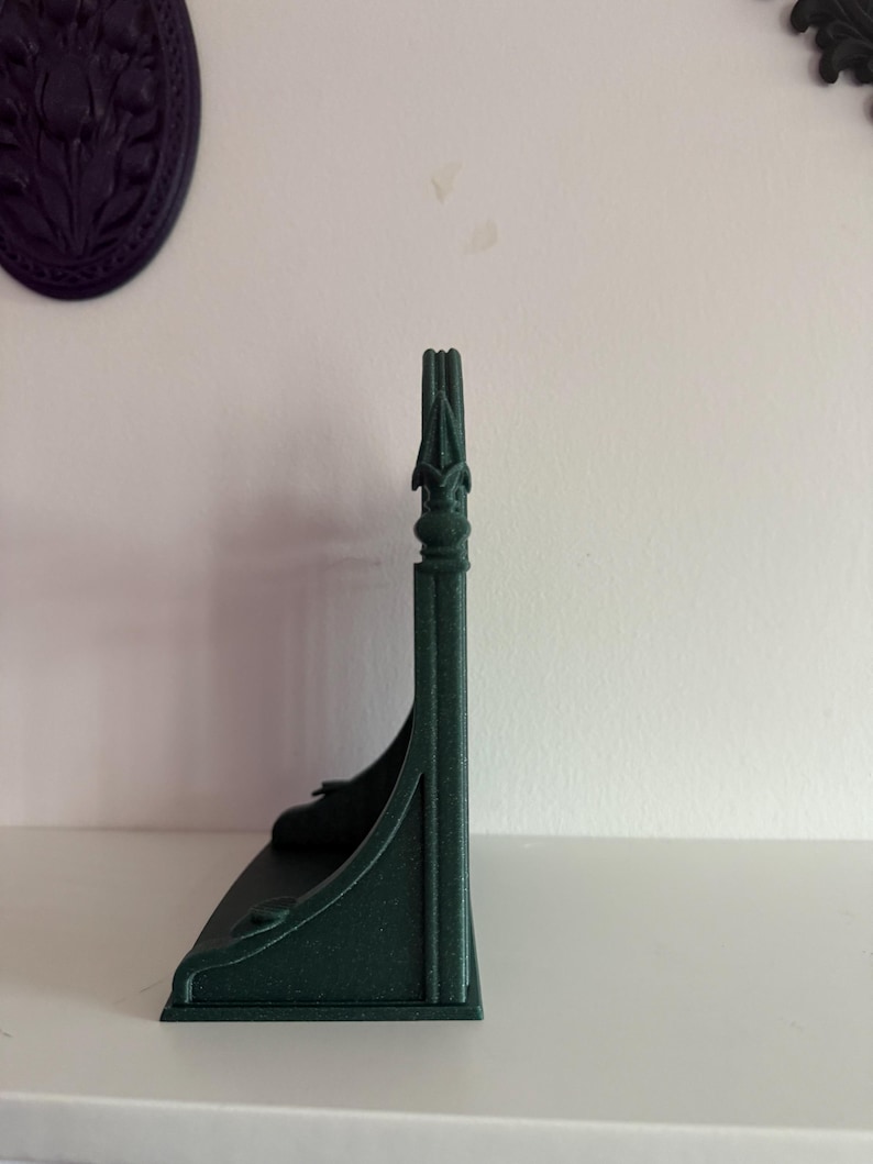 Peut inclure: Une &eacute;tag&egrave;re vert fonc&eacute; orn&eacute;e avec un dessus d&eacute;coratif. L'&eacute;tag&egrave;re a un design incurv&eacute; et est faite d'un mat&eacute;riau solide. L'&eacute;tag&egrave;re est con&ccedil;ue pour &ecirc;tre mont&eacute;e sur un mur et est probablement utilis&eacute;e pour afficher de petits objets.
