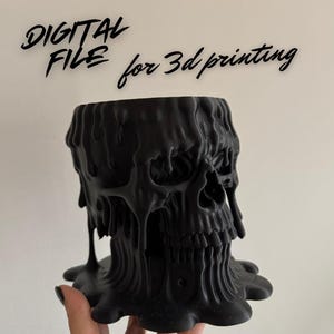 Peut inclure: Un pot de fleurs noir en forme de crâne imprimé en 3D avec un design de cire fondue. Le pot a une base large et un intérieur creux. Le texte "DIGITAL FILE for 3d printing" est écrit au-dessus du pot.