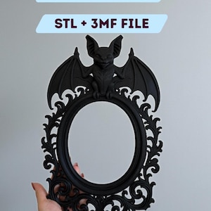 Puede incluir: Un marco ovalado negro y ornamentado con un murciélago en la parte superior. El marco tiene intrincados adornos y es sostenido por una mano. El texto en la parte superior dice "DIGITAL FILE FOR 3D PRINTING" y "STL + 3MF FILE".