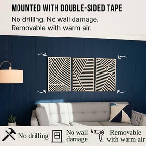 May include: Three geometric wall art panels with black and white linear designs are mounted on a dark blue wall. The text above reads "MOUNTED WITH DOUBLE-SIDED TAPE" and below, "No drilling. No wall damage. Removable with warm air."