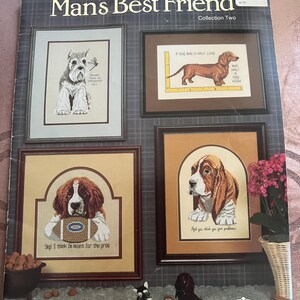 May include: A book cover titled "Man's Best Friend" by Canterbury Designs. It features framed cross-stitch dog portraits: a Schnauzer, a Dachshund, a Saint Bernard with a football, and a Basset Hound. The cover includes the text "Collection Two".