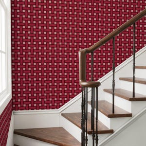 May include: A staircase with a red and beige woven pattern wallpaper on the wall. The stairs are made of wood and have a dark brown handrail. The wall is white with a window on the left.
