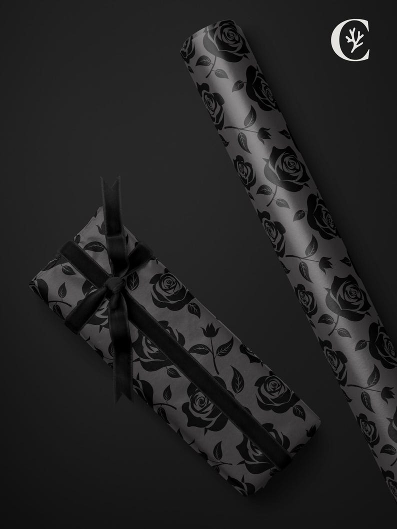 May include: A gift wrapped in gray paper with a black rose pattern, tied with a black ribbon. A roll of matching wrapping paper is also visible. The background is a solid black.