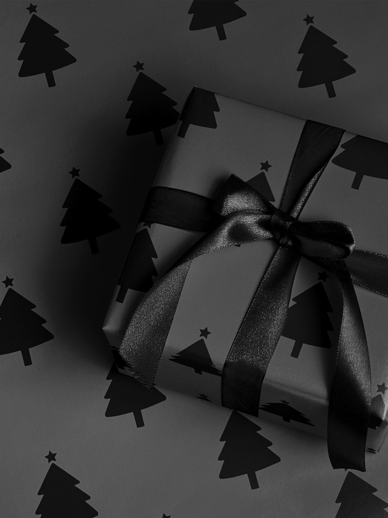 Pode incluir: Um presente embrulhado em papel de embrulho preto com um padr&atilde;o repetido de &aacute;rvores de Natal. O presente &eacute; amarrado com uma fita e la&ccedil;o de cetim preto. O fundo &eacute; o mesmo papel.