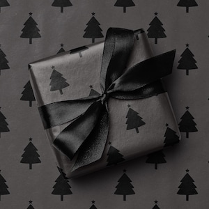 Pode incluir: Um presente embrulhado em papel preto com um padr&atilde;o repetido de &aacute;rvores de Natal. O presente &eacute; amarrado com uma fita de cetim preta, formando um la&ccedil;o no topo. O fundo &eacute; o mesmo papel de embrulho.