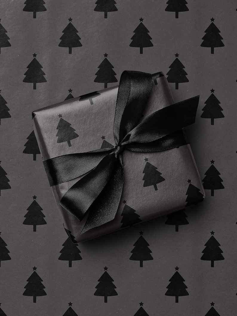 Pode incluir: Um presente embrulhado em papel preto com um padr&atilde;o repetido de &aacute;rvores de Natal. O presente &eacute; amarrado com uma fita de cetim preta, formando um la&ccedil;o no topo. O fundo &eacute; o mesmo papel de embrulho.