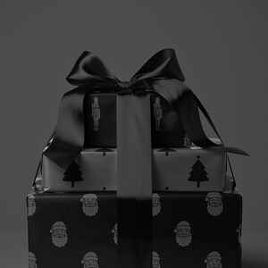 Pode incluir: Tr&ecirc;s presentes de Natal embrulhados em papel estampado a preto e branco, amarrados com um grande la&ccedil;o de cetim preto. Os desenhos do papel de embrulho incluem quebra-nozes, &aacute;rvores de Natal e rostos do Pai Natal. A imagem tem uma est&eacute;tica monocrom&aacute;tica.