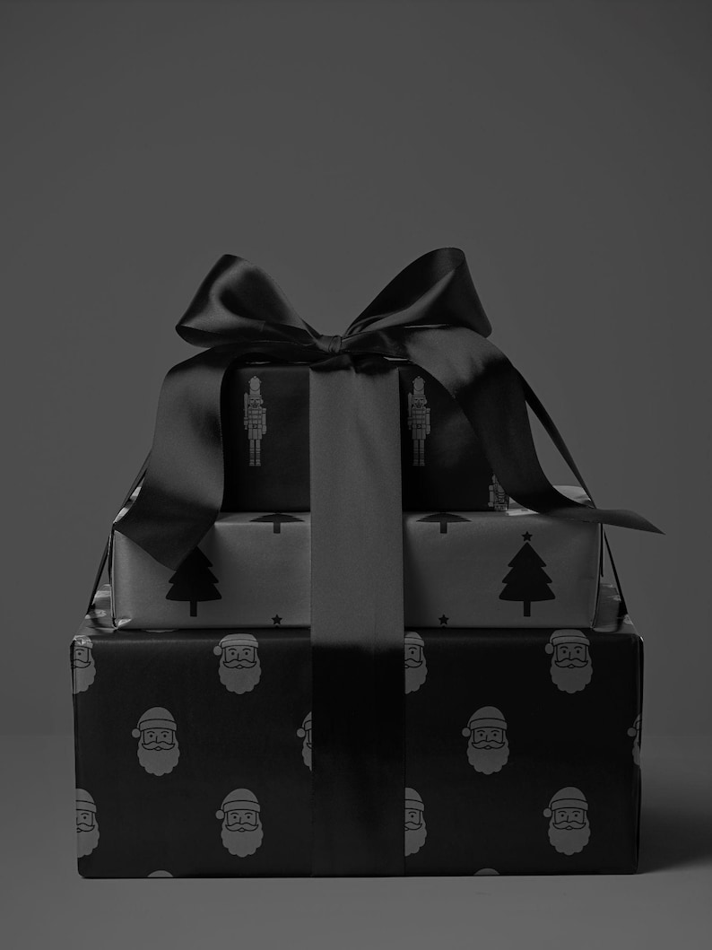Pode incluir: Tr&ecirc;s presentes de Natal embrulhados em papel estampado a preto e branco, amarrados com um grande la&ccedil;o de cetim preto. Os desenhos do papel de embrulho incluem quebra-nozes, &aacute;rvores de Natal e rostos do Pai Natal. A imagem tem uma est&eacute;tica monocrom&aacute;tica.