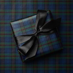 May include: A square gift wrapped in blue, green, and brown plaid paper, tied with a black satin ribbon. The ribbon is tied in a bow on top of the package. The gift is presented on a matching plaid background.