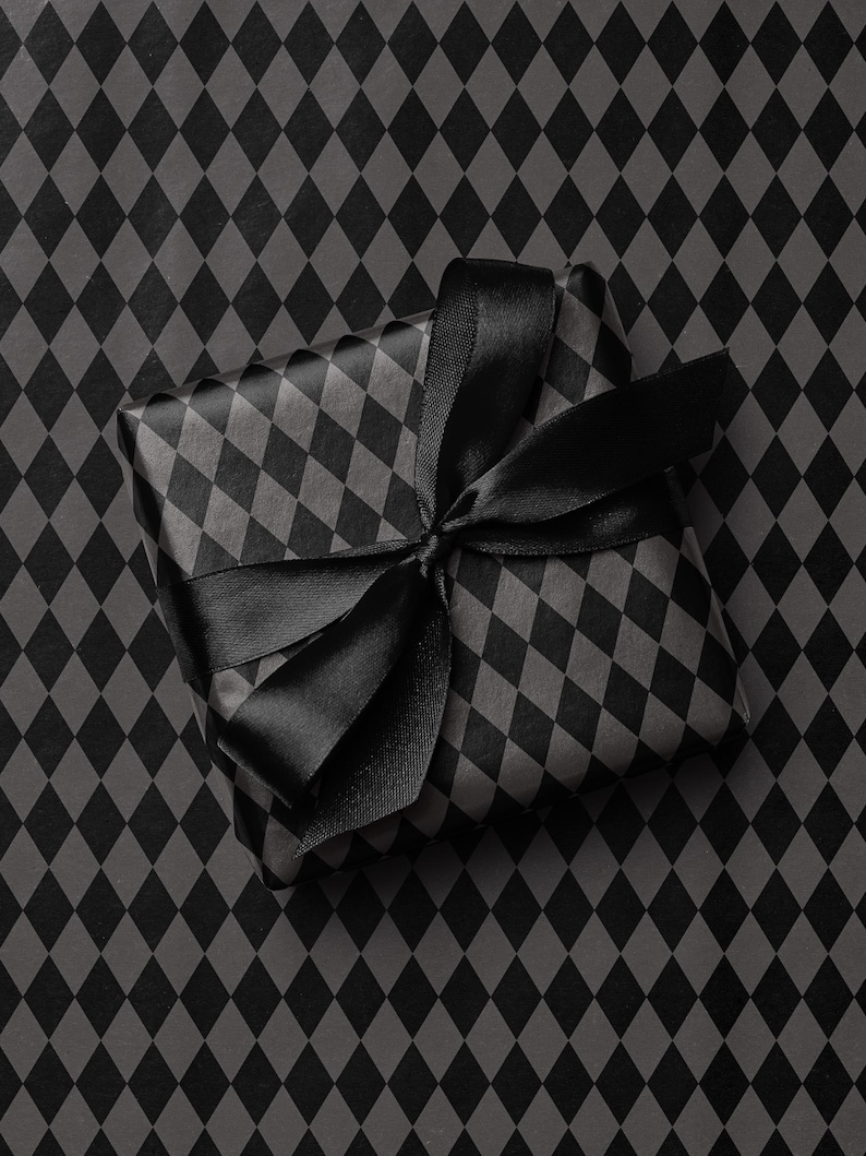 Peut inclure: Un cadeau emball&eacute; dans du papier &agrave; motifs de losanges noirs et gris, orn&eacute; d'un ruban de satin noir nou&eacute; en n&oelig;ud. Le cadeau est pos&eacute; sur un fond &agrave; motifs de losanges assortis.