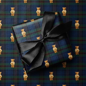 May include: A wrapped gift box with a black satin ribbon bow. The wrapping paper features a blue and green plaid pattern with repeating images of teddy bears wearing sweaters. The background also has the same teddy bear pattern.
