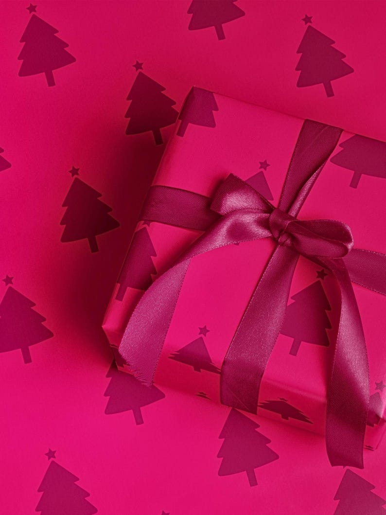 Pu&ograve; includere: Un regalo avvolto in carta magenta con un motivo di alberi di Natale magenta scuro. Il regalo &egrave; legato con un nastro e un fiocco magenta. Lo sfondo &egrave; dello stesso colore magenta con il motivo dell'albero di Natale.