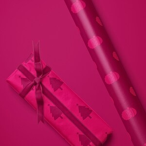 Pu&ograve; includere: Un regalo confezionato e un rotolo di carta da regalo magenta. Il regalo &egrave; avvolto con carta con alberi di Natale e un nastro. Il rotolo di carta ha un motivo ripetuto di un design festivo.