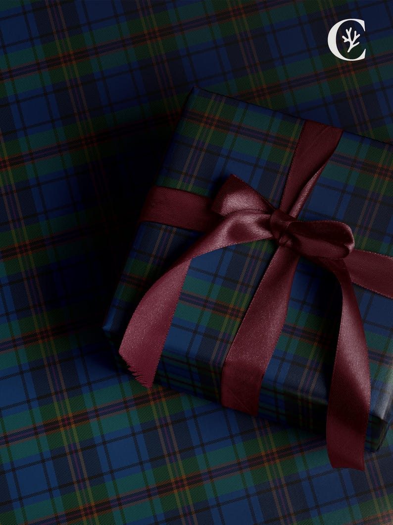 May include: A wrapped gift box with a burgundy ribbon and bow, set on a matching plaid wrapping paper. The plaid pattern features shades of blue, green, and yellow. The gift box is square-shaped.