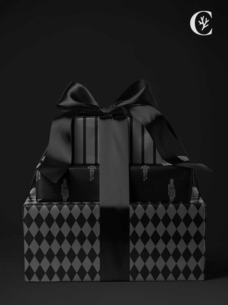 May include: A stack of wrapped gifts in black and gray. The bottom gift box has a diamond pattern, while the middle box has a soldier design. The top box has vertical stripes. A large black satin bow adorns the gifts.