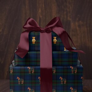 May include: Stacked gift boxes wrapped in blue, green, and black plaid paper with horse and teddy bear designs. A large burgundy bow and ribbon adorn the top. The boxes are on a wooden surface.