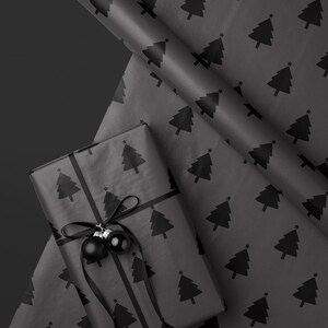 May include: A wrapped gift with black wrapping paper featuring a repeating pattern of Christmas trees. The gift is tied with a black ribbon and adorned with two black ornaments. A roll of matching wrapping paper is visible.