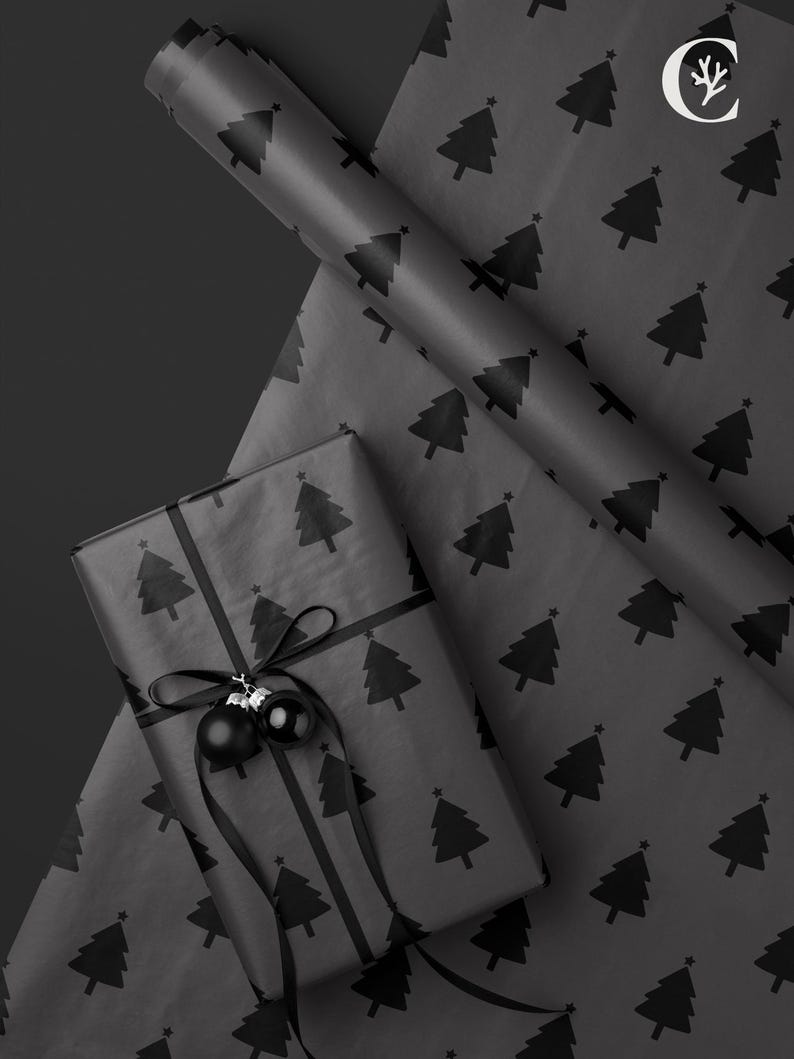 May include: A wrapped gift with black wrapping paper featuring a repeating pattern of Christmas trees. The gift is tied with a black ribbon and adorned with two black ornaments. A roll of matching wrapping paper is visible.