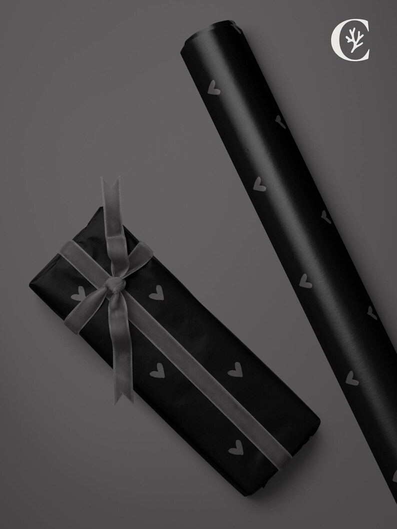 May include: Black gift wrap with a repeating heart pattern, a wrapped gift with a gray ribbon, and a roll of matching wrapping paper. The gift is tied with a gray ribbon.