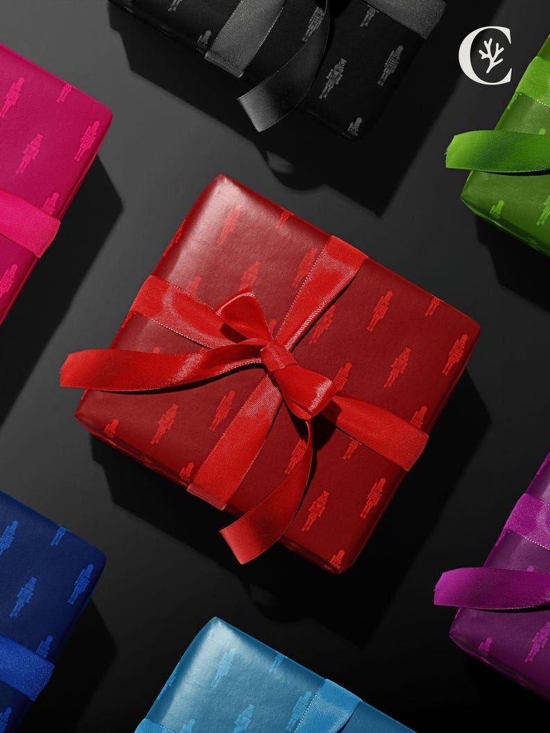 Op de afbeelding: Overzichtsfoto van ingepakte cadeaus in verschillende kleuren, waaronder rood, roze, blauw, groen en paars. Elk cadeau is verpakt in papier met patronen en vastgebonden met een bijpassend satijnen lint en strik. De cadeaus zijn gerangschikt op een zwarte ondergrond.