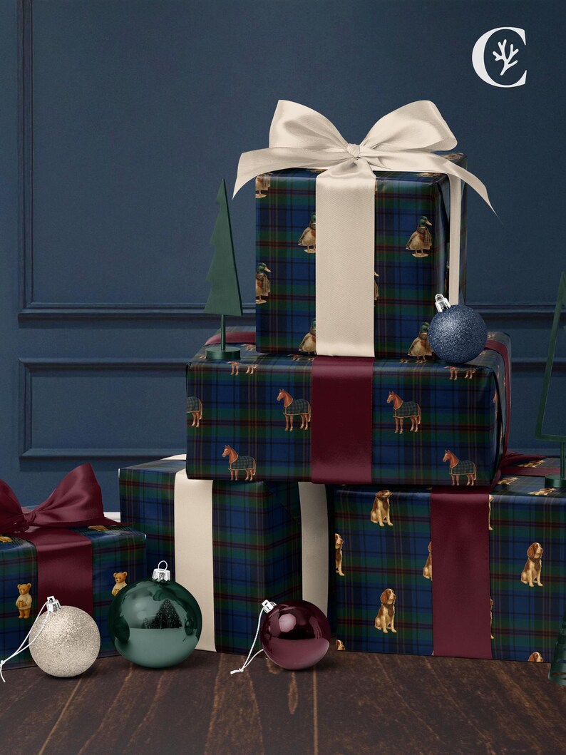May include: Wrapped gifts with plaid patterned paper featuring ducks, horses, and dogs, tied with white and burgundy ribbons. Decorative Christmas ornaments in silver, green, and burgundy are arranged on a wooden surface, with a dark blue background.