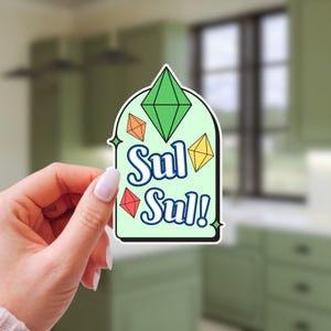 May include: A sticker with a light green background and a white border. The sticker features a green diamond shape at the top, with three smaller geometric shapes in orange, yellow, and red. The words "Sul Sul!" are written in blue with a white outline.