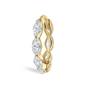 Puede incluir: Un anillo de oro con una serie de diamantes talla marquesa. Los diamantes están engastados en un patrón continuo alrededor de la banda, creando un diseño brillante y elegante. El anillo está sobre un fondo blanco.