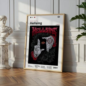 May include: A framed poster titled "Hellsing" in red gothic lettering. The artwork depicts hands framing an eye, with detailed illustrations on a black background. The poster is propped against a wall.