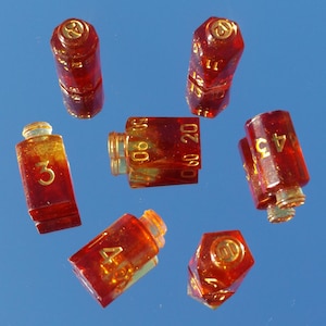 May include: A collection of small, transparent, amber-colored dice with gold-colored accents and numbers. The dice are arranged against a reflective, blue background. The numbers 3, 4, 45, 11, 10, 20, 60, and 90 are visible.
