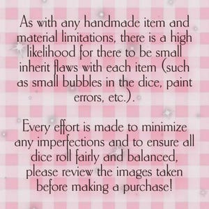 May include: Text on a pink and white checkered background. The text discusses potential minor flaws in handmade items like dice, due to material limitations. It encourages reviewing images before purchase.