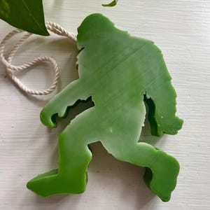 May include: Green Bigfoot silhouette hanging ornament with a white twine string.