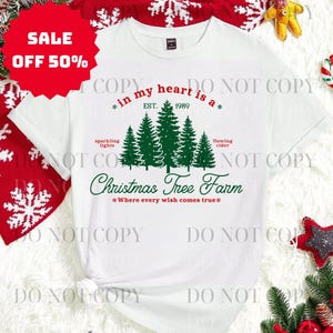 May include: White t-shirt with a green Christmas tree graphic and the text "in my heart is a * EST. 1989 * Christmas Tree Farm *Where every wish comes true*". A red sale tag is in the upper left corner.