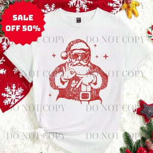 May include: White t-shirt with a red graphic of Santa Claus wearing sunglasses and making a hand gesture. The shirt has a crew neck and short sleeves. A red sale tag with "OFF 50%" is in the upper left corner.