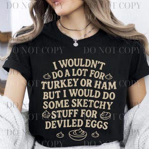 Può includere: T-shirt nero con la scritta "I wouldn't do a lot for turkey or ham but I would do some sketchy stuff for deviled eggs" in color beige. La maglietta ha uno scollo tondo.
