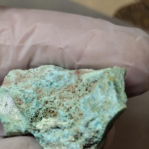 Könnte beinhalten: Nahaufnahme eines grob behauenen Gesteins mit türkisfarbenen und braunen Farbtönen. Das Gestein hat eine poröse Textur und scheint ein Mineralpräparat zu sein. Das Bild ist gut beleuchtet und hebt die natürlichen Farben und Texturen hervor.