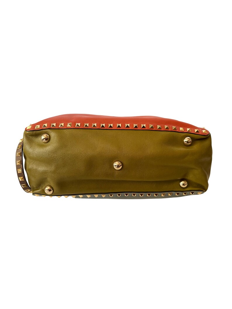 Puede incluir: Un bolso de mano de cuero con un dise&ntilde;o de bloques de color. La secci&oacute;n superior es naranja, la del medio es verde oliva y la inferior es verde azulado apagado. Se ven tachuelas y herrajes dorados.