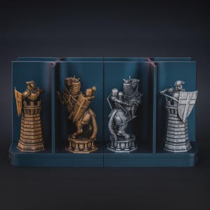 Puede incluir: Un juego de ajedrez con cuatro piezas: una torre dorada, un caballero dorado, un caballero plateado y una torre plateada. Las piezas se exhiben en un soporte azul oscuro segmentado.