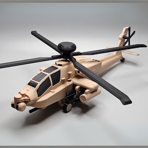 Puede incluir: Un modelo de helicóptero beige y negro con cuatro palas de rotor. El modelo tiene detalles, incluyendo una cabina, armas y rotor de cola. El helicóptero es un juguete o artículo de colección.