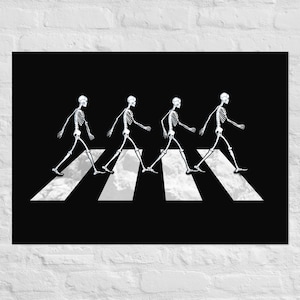 May include: Black poster featuring a parody of the iconic Abbey Road album cover. Four white skeleton figures are walking across a white crosswalk against a black background. The poster is mounted on a white brick wall.