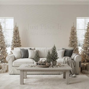 Könnte beinhalten: Ein gemütliches Wohnzimmer mit weißem Sofa, dekorativen Kissen und einem Holztisch. Auf dem Tisch befindet sich ein Korb mit Tannenzapfen und Ornamenten. Beleuchtete Weihnachtsbäume flankieren die Fenster und schaffen eine festliche Atmosphäre. Die Wand zeigt "Just Place It".