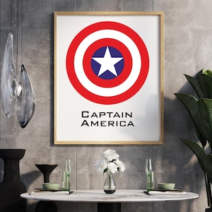 K&ouml;nnte beinhalten: Gerahmter Druck mit dem Schild von Captain America. Das Schild ist ein roter Kreis mit einem wei&szlig;en Stern in einem blauen Kreis in der Mitte. Der Text "CAPTAIN AMERICA" ist darunter in Schwarz gedruckt. Der Druck ist in einem Holzrahmen.