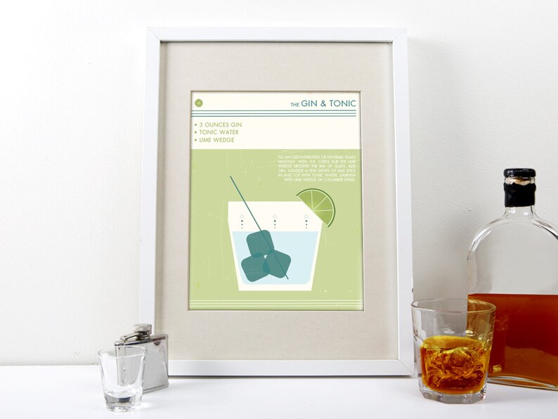 May include: A framed illustration of a Gin & Tonic cocktail recipe with a green background. The illustration shows a glass with ice cubes, a lime wedge, and a straw. The recipe lists the ingredients: 3 ounces gin, tonic water, and a lime wedge.